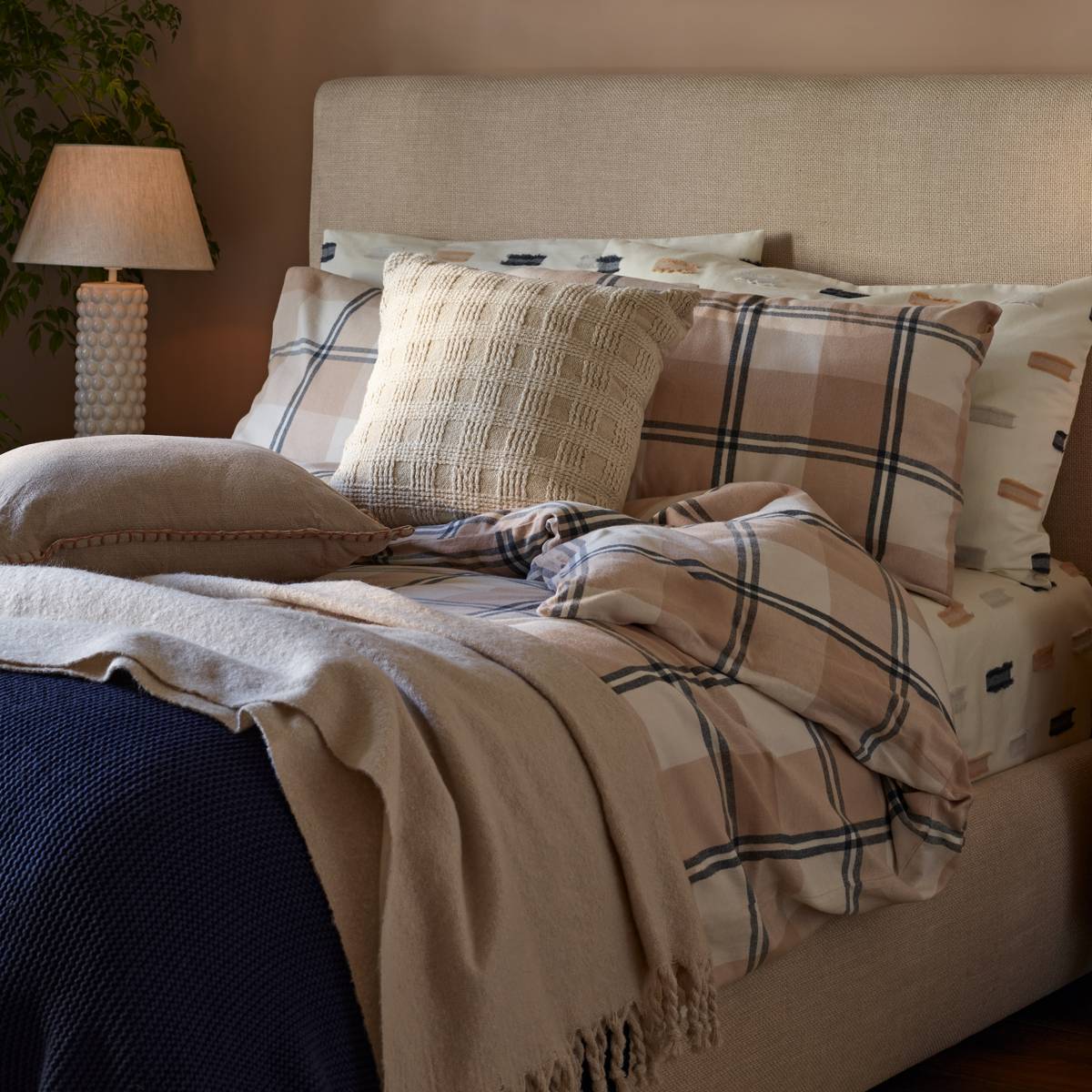 Bed made up with patterned, neutral and navy bedding 